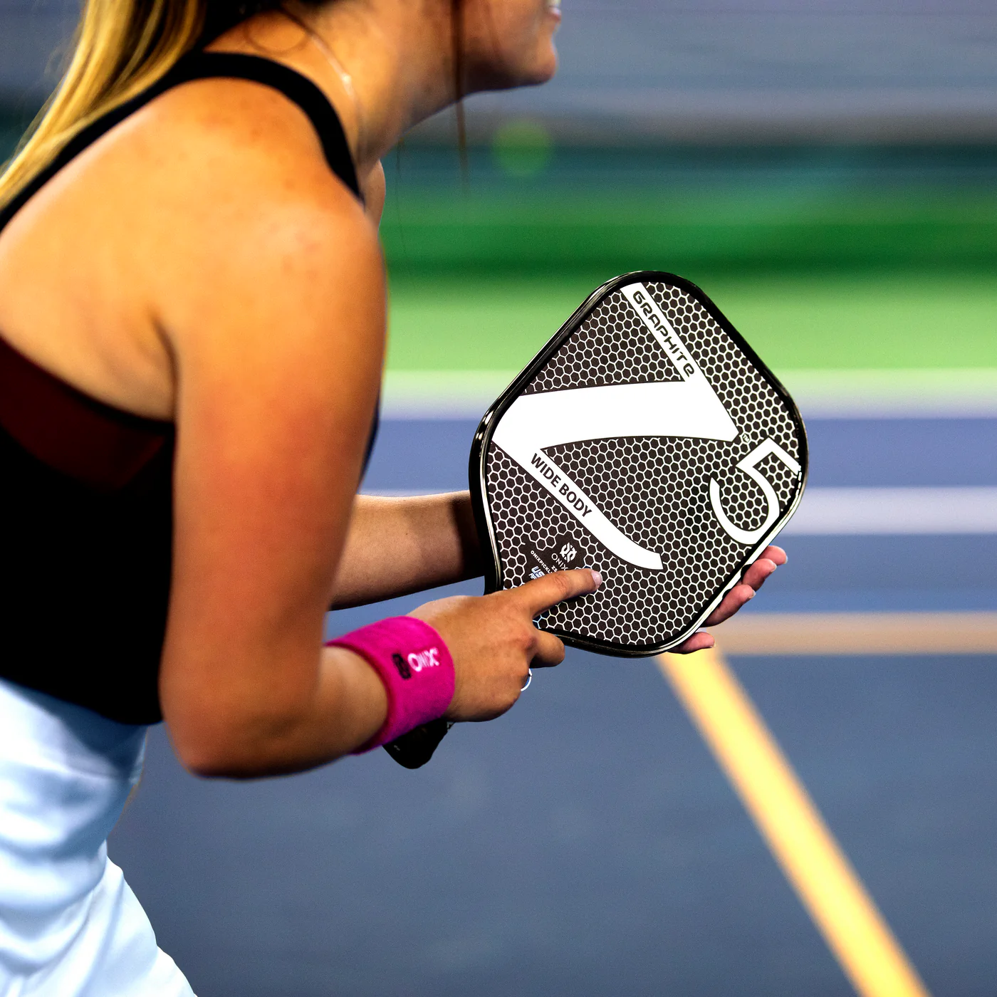An intermediate player carefully placing a third shot drop with a graphite paddle.